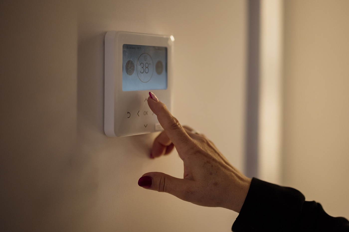 Hand adjusting a digital home thermostat